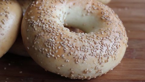 Piled fresh bagels on a wooden tray. HD video.