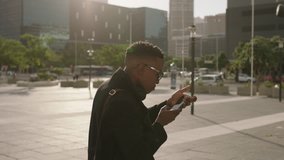 portrait of trendy african american man student taking photo of urban city using smartphone video technology happy enjoying sightseeing travel real people series