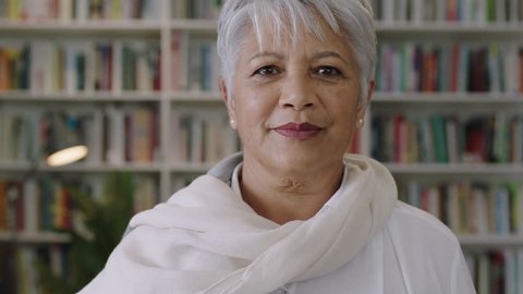 portrait of friendly indian middle aged teacher standing in library smiling Stock-video