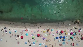 Nice beach in Odessa in Ukraine. On it there are many multicolored umbrellas with beach mats. Relaxing tourists are sunbathing and swimming in the sea. Aerial video recording.