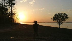 A man exercising on a sunset river, Sunset backlit teen doing exercise