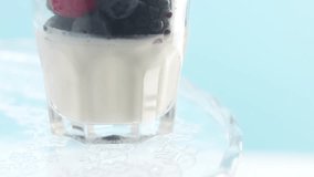 tilted clip of woman's hand picked a raspberry from a glass with greek yogurt and berries Minimalism food video