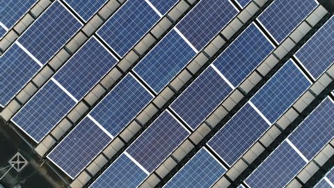 Aerial top down view moving up above solar panels PV modules mounted on flat roof photovoltaic solar panels absorb sunlight as a source of energy to generate electricity creating sustainable energy 4k