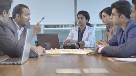 A business team of mixed gender and ethnicity taking an important and critical financial decision in a conference meeting. A serious and focused creative office workers interacting on upcoming project