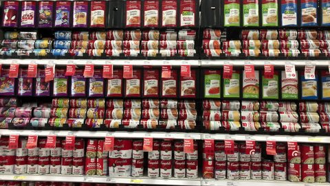 Alameda, CA - April 06, 2018: 4K HD Video panning across grocery shelves with cans of Campbell's soups. Campbell Soup Company, an American selling products in 120 countries around the world.