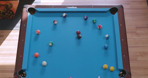 Overhead View of Breaking Racked Pool Balls in Eight-Ball Formation on Blue Billiards Table