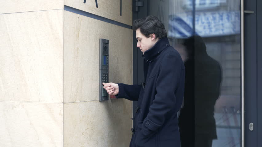 Young teenager input open code on intercome and enter apartment building
