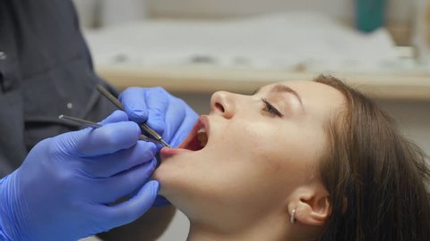 Male dentist treating teeth to young woman patient in clinic.