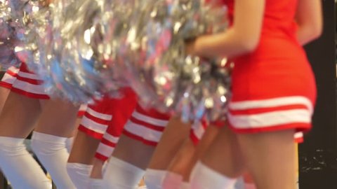 Girls cheerleaders in a red dresses dancing with pompoms