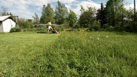 SAINT-PETERSBURG, RUSSIA - summer, 2017 The girl mowing the lawns. Shot in 4K (ultra-high definition (UHD)), so you can easily crop, rotate and zoom, without losing quality! Real time.