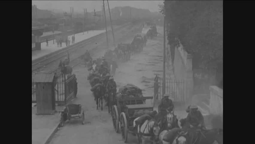 CIRCA 1918 - The 319th Field Artillery Regiment leaves railroad yards in Toul traveling in wagons through a gate toward the Front in France in WWI.