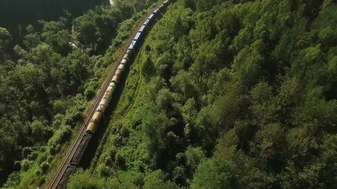 Freight train carries an electric locomotive by two-sided railway along the river in the Ural Mountains - Aerial Photography, top view