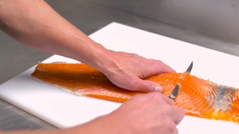 food, small business and seafood cooking concept - male chef slicing smoked salmon fillet at restaurant kitchen