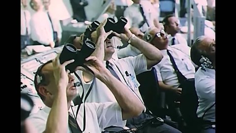 CIRCA 1969 - Men at launch control watch Apollo 11's progress through binoculars.
