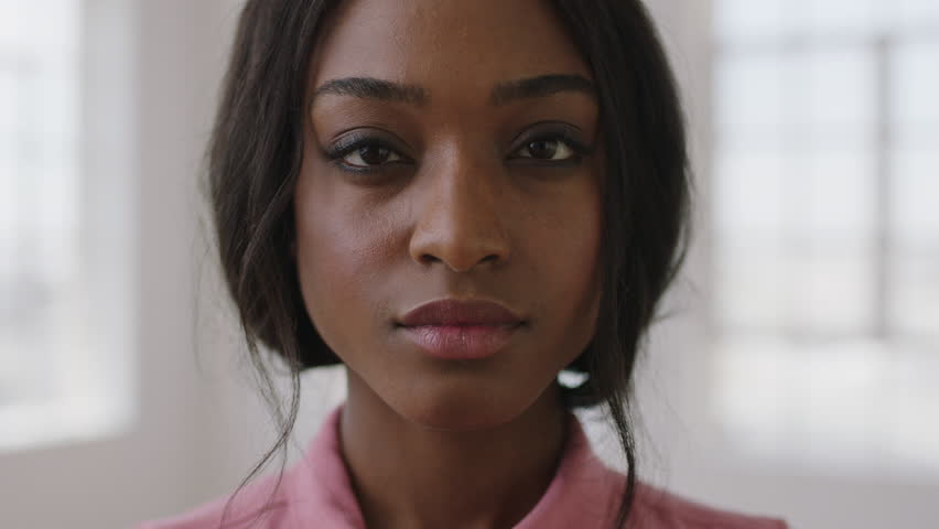 Close up slow motion portrait of young stylish african american woman looking serious intense at camera wearing pink blouse skin care concept real people series | Shutterstock HD Video #1009612064