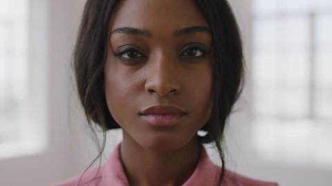 close up slow motion portrait of young stylish african american woman looking serious intense at camera wearing pink blouse skin care concept real people series
