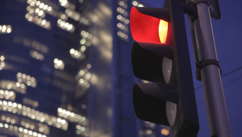 Stoplight in a city. Traffic signal light changes from red to green at night. A traffic light in the night time period. The skyscraper stands in the background of the stop signal. Royalty-Free Stock Footage #1009620398