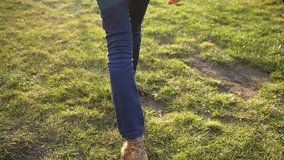 Slim slander long legs girl in jeans and sneakers walks the green countryside meadow grass, back glide camera