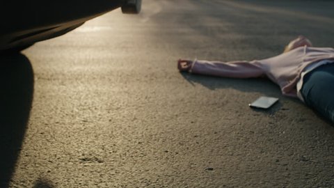 Girl laying in street with cell phone near car bumper after accident / Cedar Hills, Utah, United States