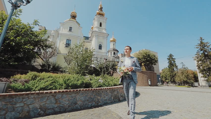Groom coming to bride. Walks on old european city street. Newlyweds.