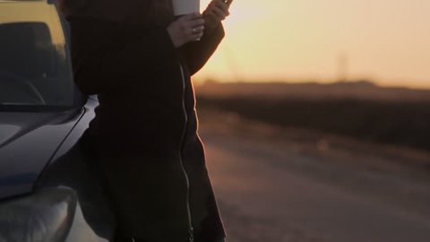 Young attractive woman is using a mobile phone at sunset.