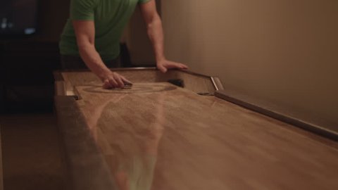 Man playing shuffleboarding on table in 4k.