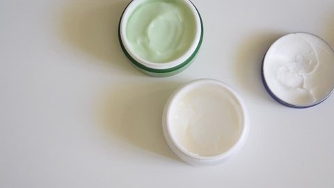 Top view of different opened body/face creams on white background. Cosmetic products concept