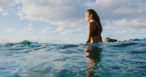 Beautiful young woman surfing at sunset, underwater view
