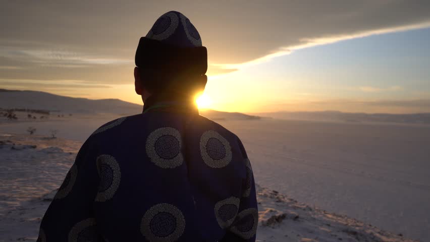 Gimbal Scenic Back Portrait Close Shaman Chief Buryat Costume authentic historical original. Looks into distance horizon snowfield landscape frost. Winter dawn bright sun orange clouds. Baikal Russia