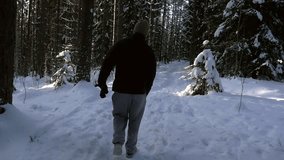Man walking in a snowy forest, Slow motion view following a young male, hiking in a frozen forest, on a freezing cold winter day, in Sipoonkorpi national park, Uusimaa, Finland