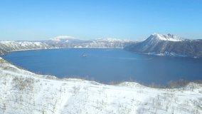 4K Aerial video of Lake Mashu in Hokkaido, Japan in the winter with snow surrounded and deep blue lake under the clear sky