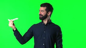 Handsome man with beard holding a toy airplane on green screen chroma key
