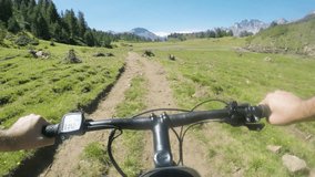 POV man riding e-bike on hill near lake.Mtb action cyclist exploring trail path near mountains.Electrical bike active people sport travel vacation in Europe Italy Alps outdoors in summer.4k video