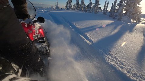 SLOW MOTION, CLOSE UP: Snowmobile takes off and sprays snow into the camera. Sled riding race in back country. Snowmobile tracks spinning, kicking up fresh snow and spraying snowflakes. Snowmobiling