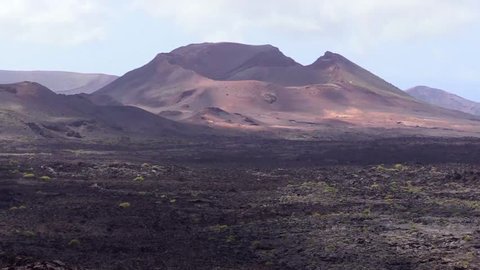 Amazing view of volcano mountain in Timanfaya National Park with astonishing colors, exemplary crater with wonderful light and shadows from the sun and the clouds - Lanzarote 1080p