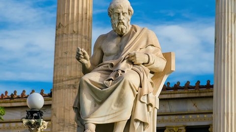 Statue of the great Greek philosopher Plato on a marble chair, background of sky and marble columns.