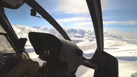 Aerial view from a Interior of helicopter cockpit with instruments panel flying over winter mountains peaks