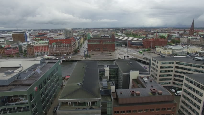 Aerial drone shot flying over canal and city buildings in Malmö, Swedenn
