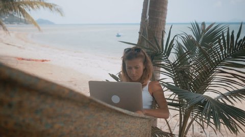 Woman freelancer works on the beach in hammock