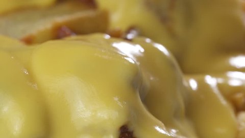 Macro closeup chef putting melted cheese on top of the french fries chips with chilli con carne sauce - video in slow motion