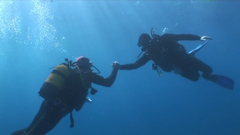 scuba divers ascending end of dive shaking hands underwater enjoyment happy people
