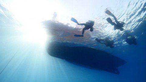 scuba divers going back  to  the boat underwater surface background  with sun beams and rays ocean scenery