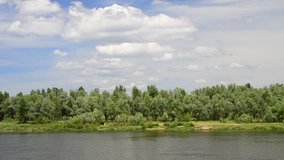 Summer landscape with Desna river and vibrant lush green trees and white cumulus clouds in blue sky. Shot in Kiev oblast, Ukraine