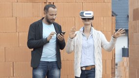 Couple of architects with vr goggle and smartphone setting up visual project of new home at construction site 

