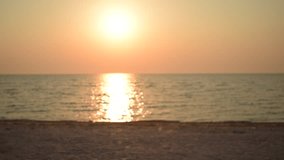 Unidentifiable man walks along shore on beach at dawn during sunrise in the morning. Defocused video.