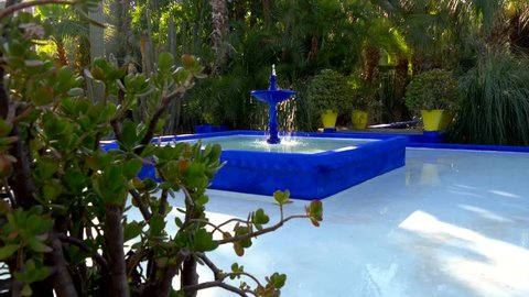 Blue fountain in Majorelle Garden, botanical garden and artist's landscape garden in Marrakech, Morocco. Crane shot.