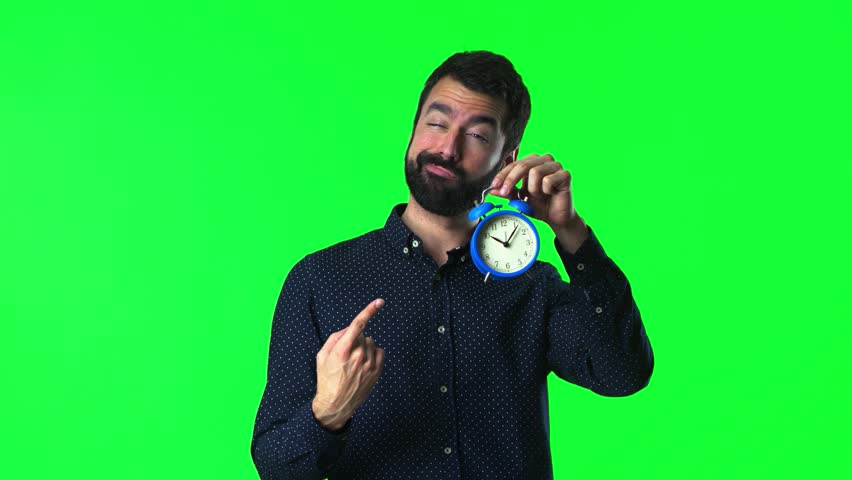 Handsome man with beard  holding vintage clock on green screen chroma key