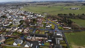 Aerial drone footage of suburban houses and fields in Scotland, UK