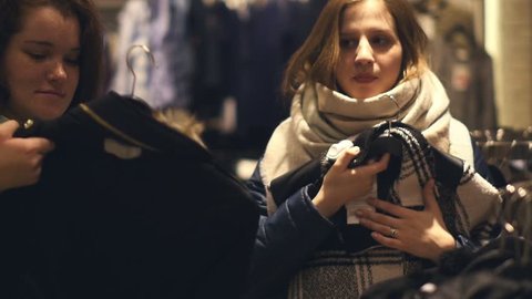Two young women shop at the store choosing warm winter clothes