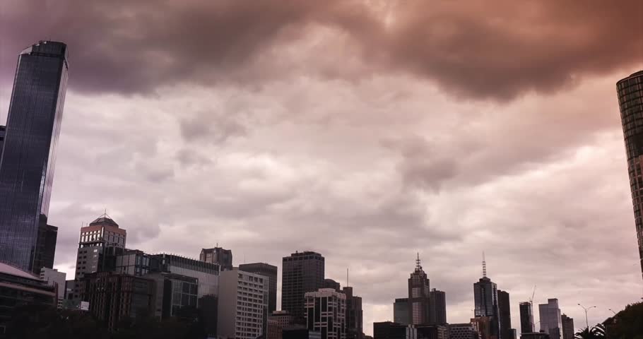 Cinematic time lapse of skyscraper in Melbourne Centre Business District during sunset with gloomy cloud and sky changing color.All logotype removed.Camera zoom out.